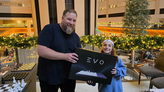Two smiling participants at NYC Metro Scholastic Championships holding an EVO chess set, celebrating their experience.