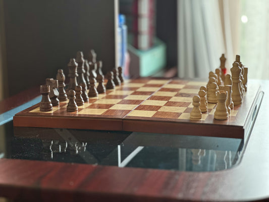A chess game setup with brown and beige pieces on a wooden chessboard, ready for strategic play.