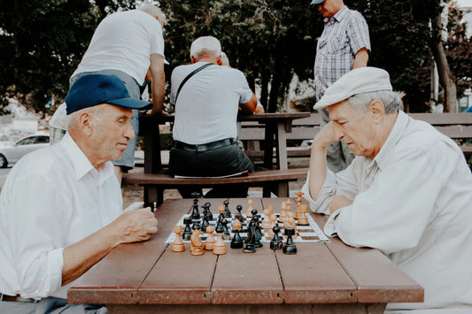 Two elderly men playing chess outdoors, demonstrating strategies in How To Defend in Chess.
